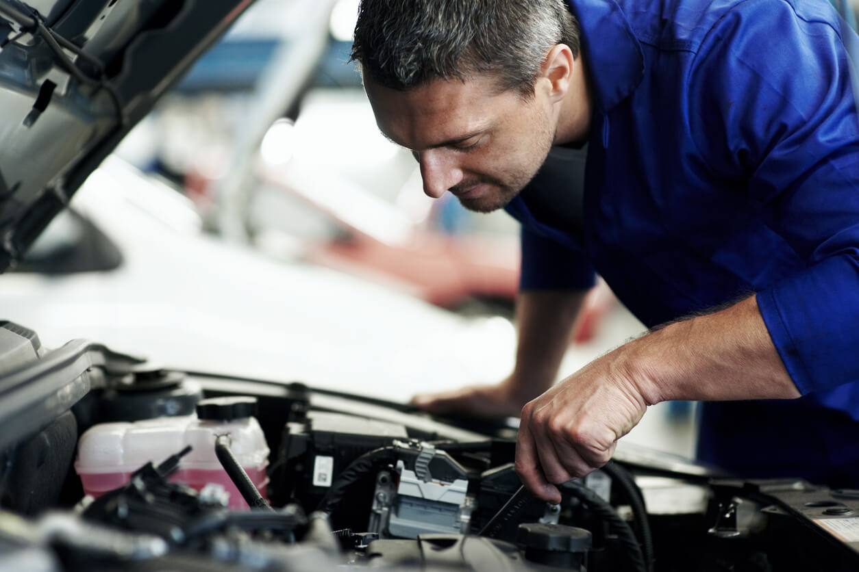 Automotive mechanic inspecting car engine inside repair shop